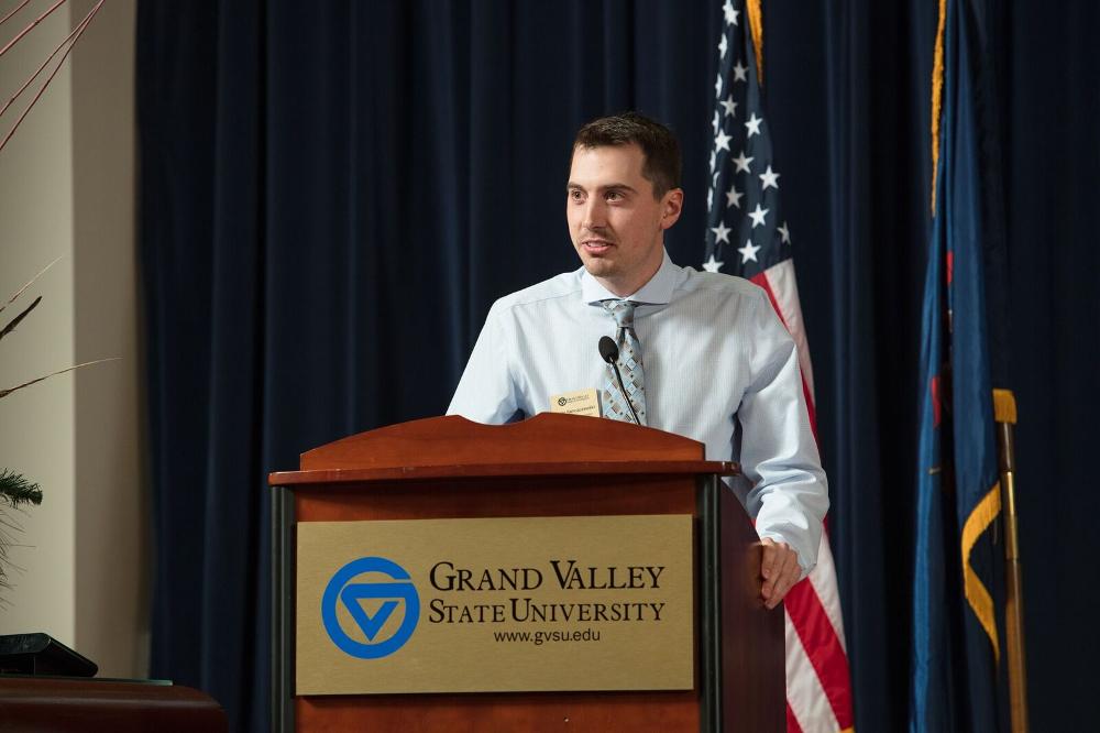 A  man standing at a GVSU podium on stage